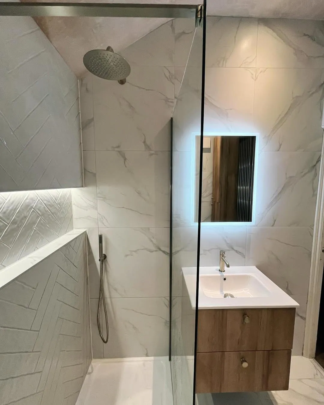 Elegant bathroom with marble tiles, glass shower and wood vanity